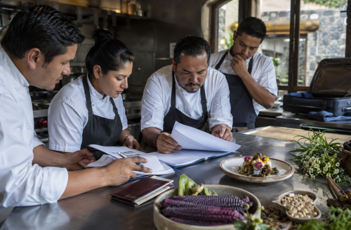 Chef y brigada de cocina revisan documentos de una convocatoria internacional junto a ingredientes del Estado de México y un platillo listo para presentar
