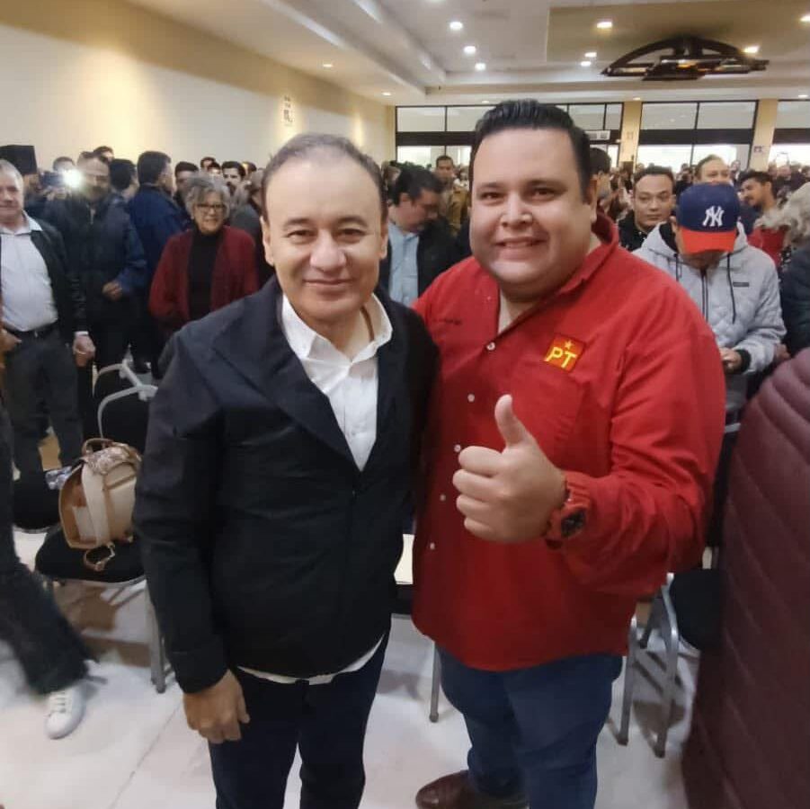 Dos asistentes posan durante un encuentro político en Hermosillo; uno viste una camisa roja con el emblema del PT